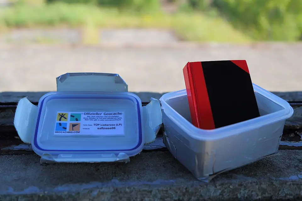 Geöffnete Geocache-Dose mit Logbuch unter einer Holztribüne in der Lieberoser Heide